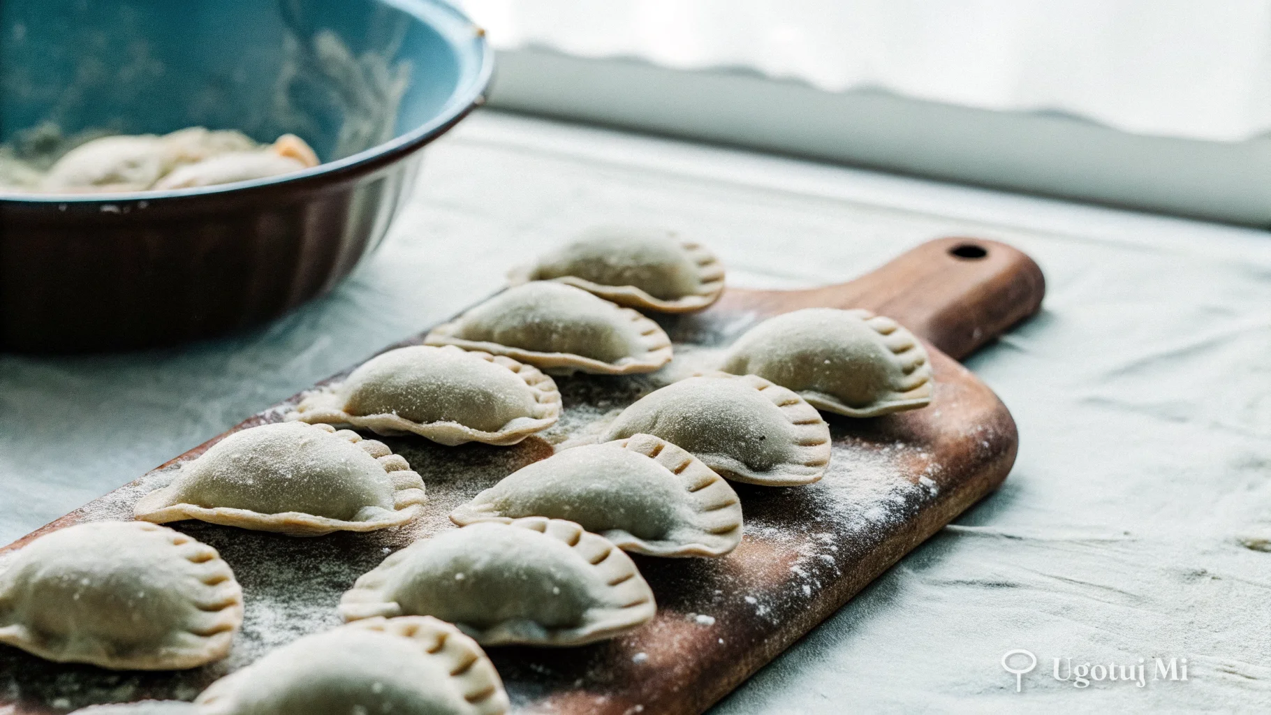 Surowe uszka z nadzieniem grzybowym ułożone na oprószonej mąką desce | ugotujmi.pl