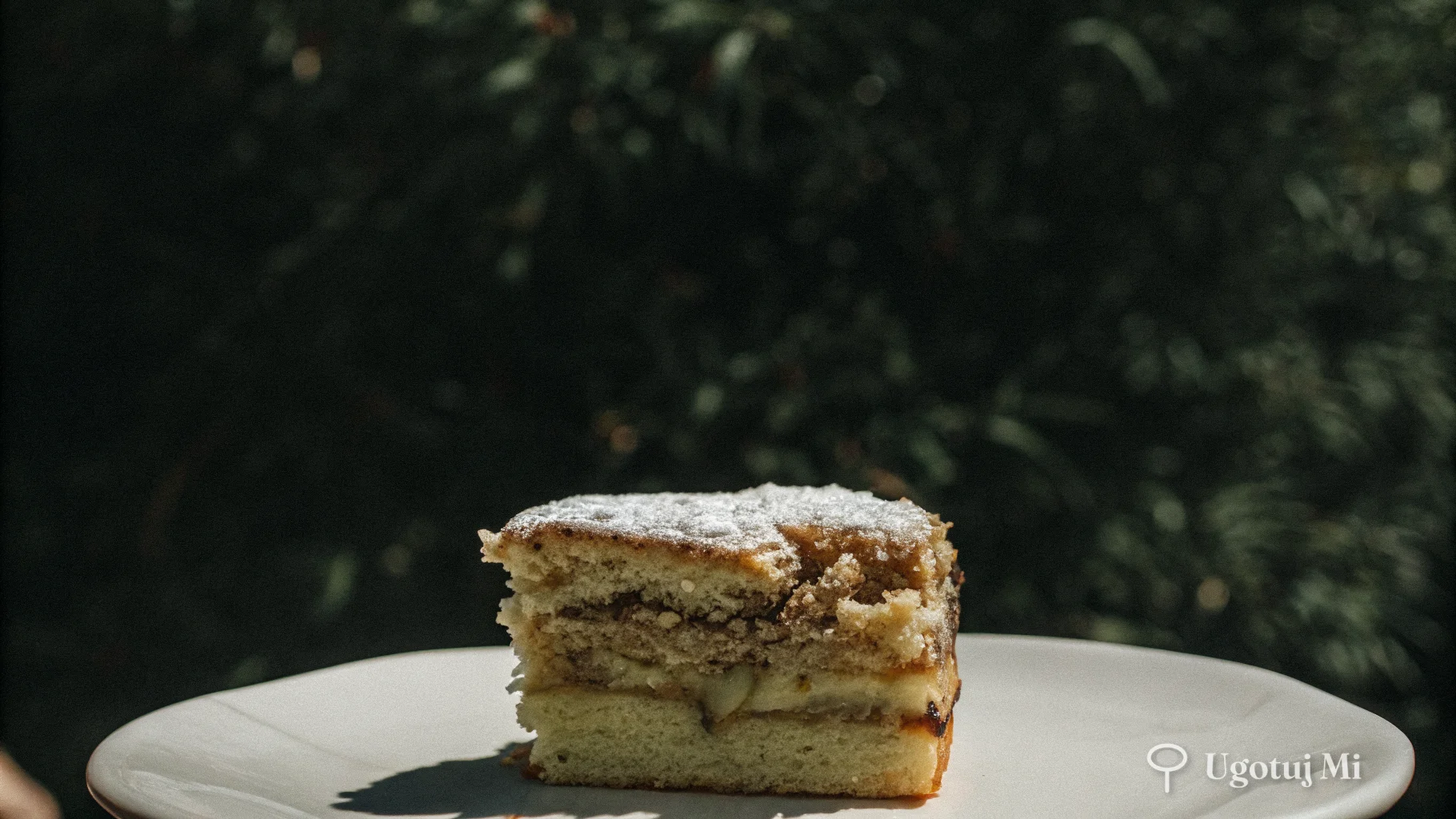 Przekrojony kawałek jabłecznika pokazujący wilgotne warstwy ciasta i jabłkowe nadzienie | ugotujmi.pl