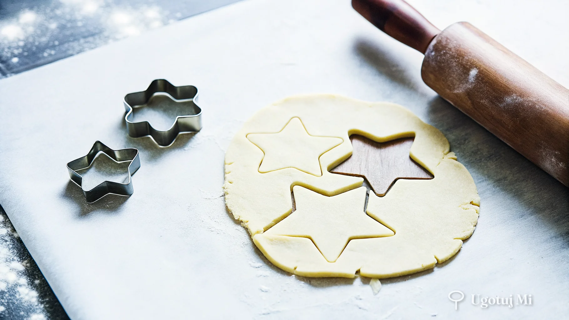 Surowe ciasto kruche wałkowane na blacie z foremkami do wycinania ciasteczek | ugotujmi.pl