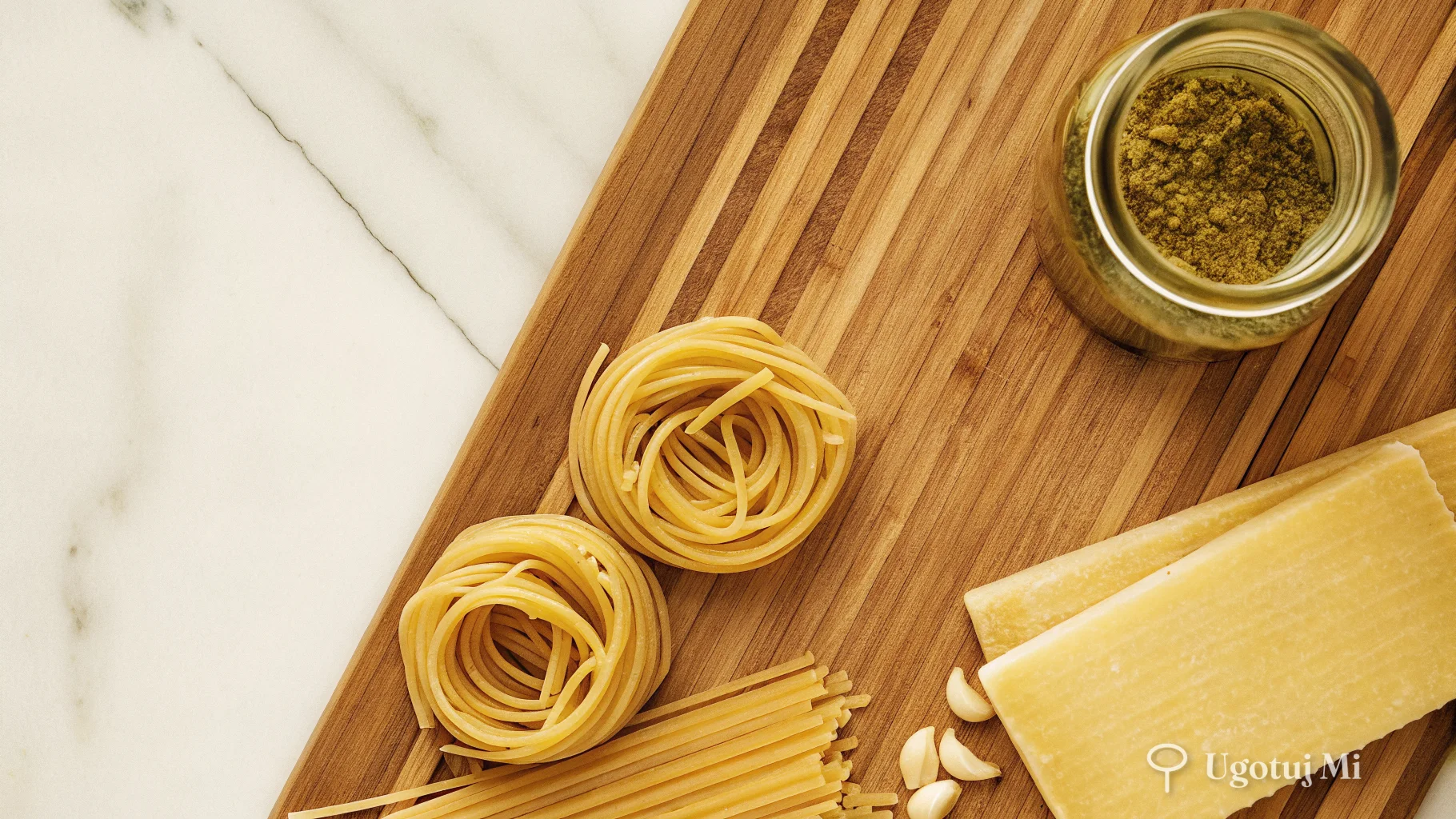 Składniki do makaronu z pesto: słoiczek pesto, suszone pomidory, makaron, czosnek i parmezan na jasnym tle | ugotujmi.pl