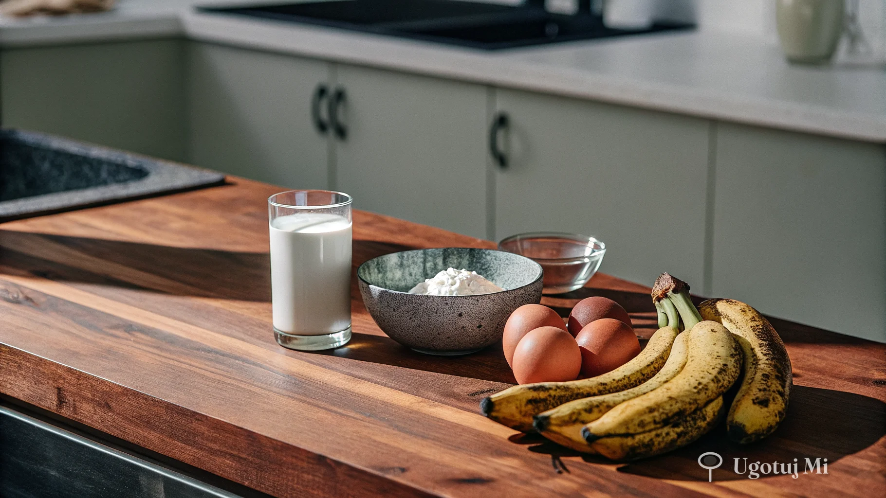 Składniki na racuchy z bananem rozłożone na drewnianym blacie – dojrzałe banany, jajka, mąka i maślanka | ugotujmi.pl