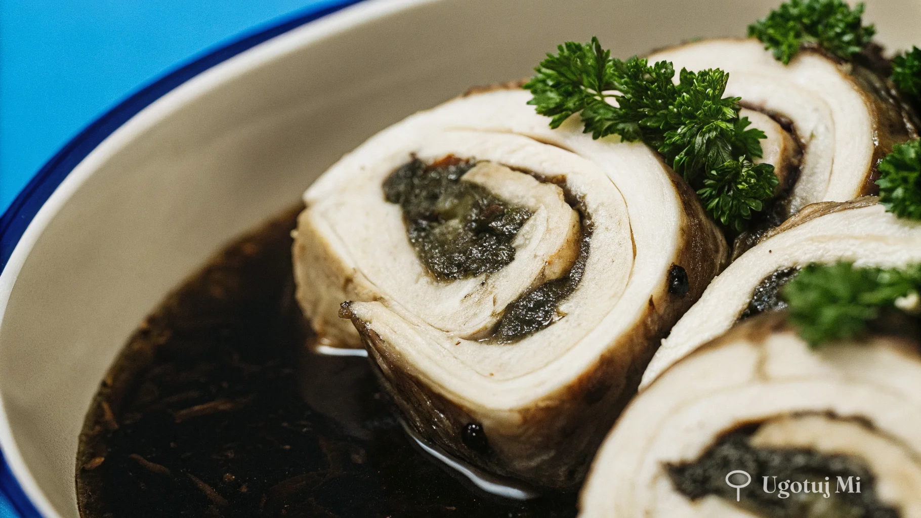 Zbliżenie na mięso zrazów pokryte błyszczącym sosem cebulowym z natką pietruszki | ugotujmi.pl